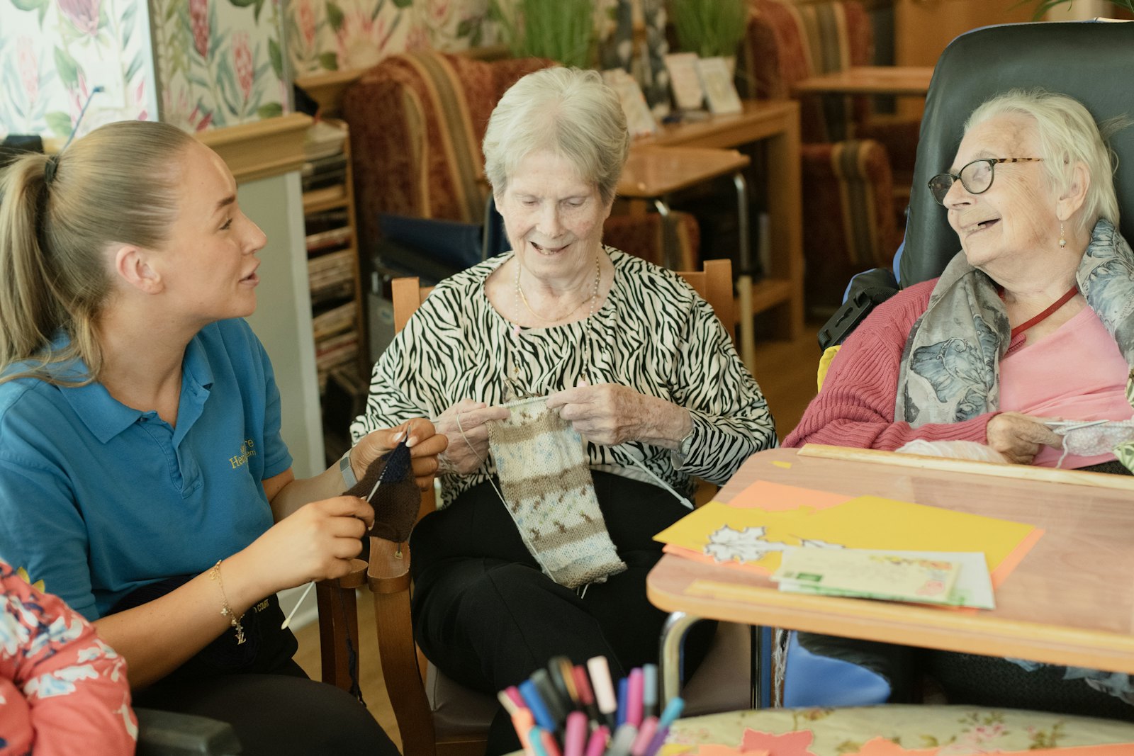 Caregiver helping two elderly women with their knitting